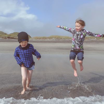 To børn leger i vandkanten på stranden