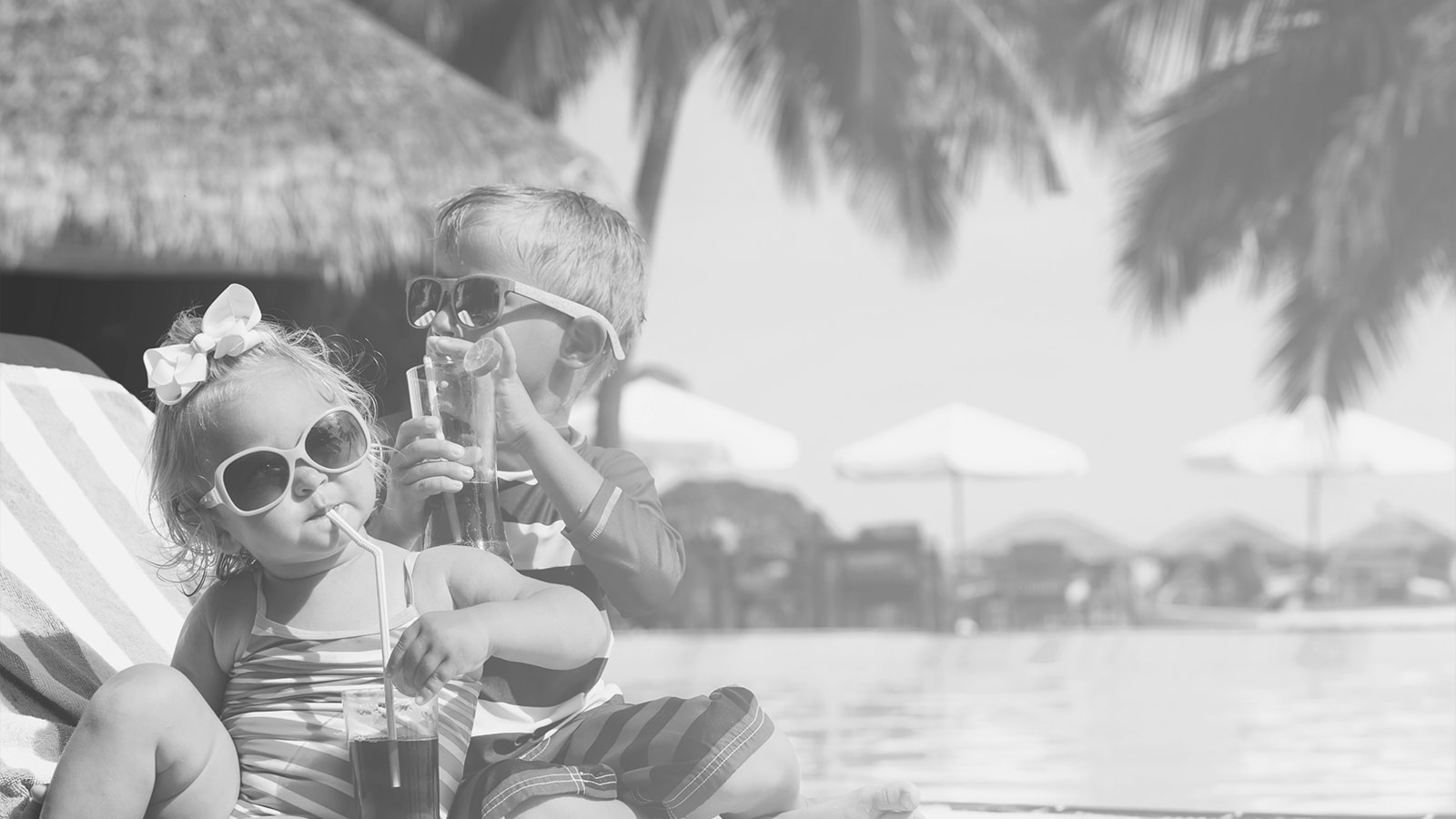 En dreng og en pige drikker juice ved poolen