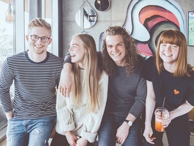 En gruppe unge sider sammen på en café og smiler