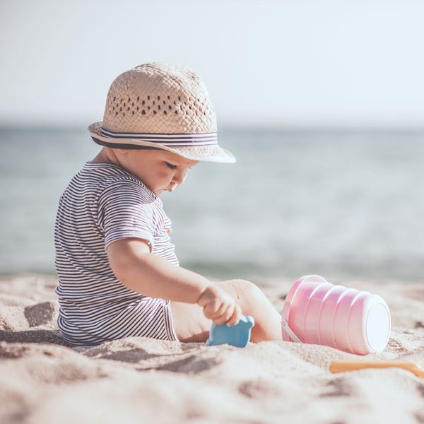 Et barn leger med skovl på en strand