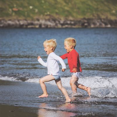 To drenge løber i vandkanten på stranden