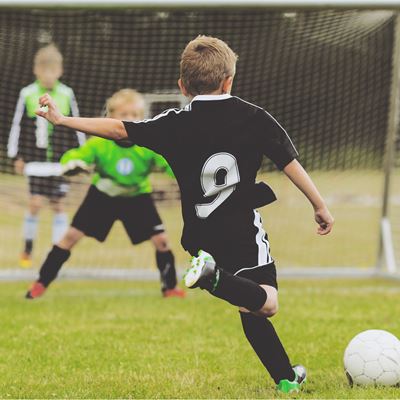 En lille dreng skal til at sparke på mål i en fodboldkamp