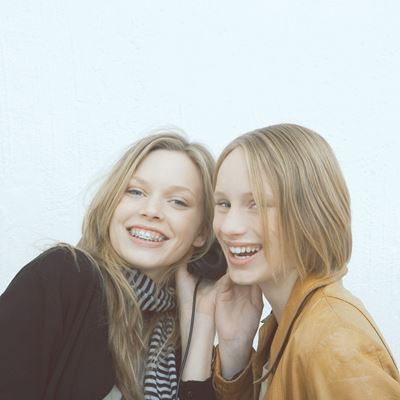 To teenagepiger lytter til musik på et sæt hovedtelefoner og smiler