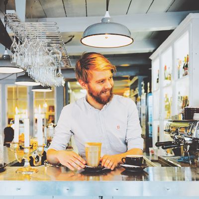 En ung mand arbejder som tjener på en café