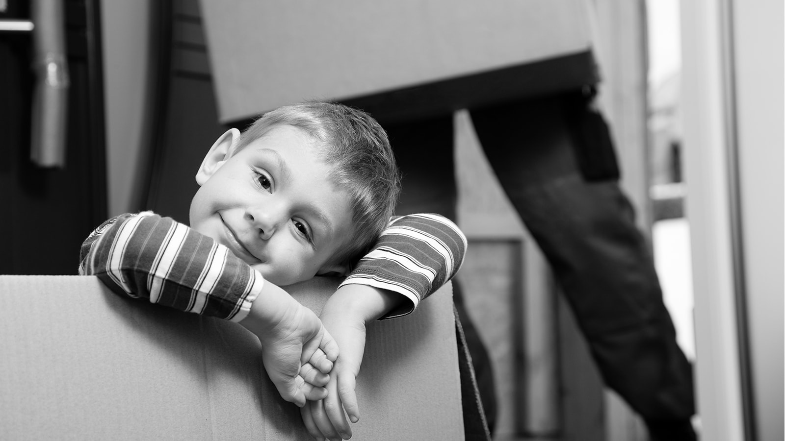 En lille dreng sidder i en flyttekasse