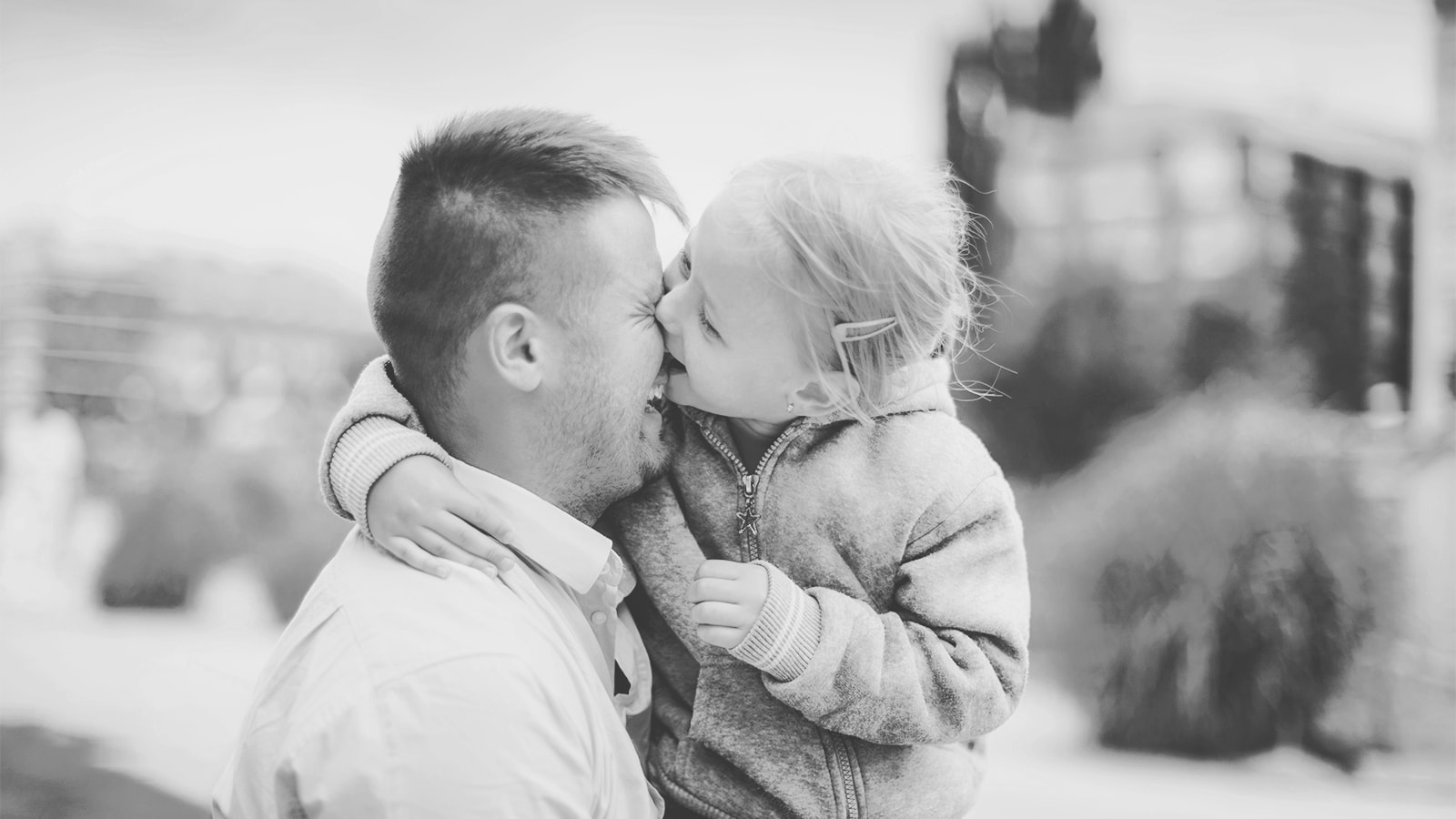 En lille pige bider sin far i næsen, mens de begge griner