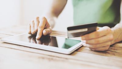En mand betaler online på sin tablet med sit betalingskort