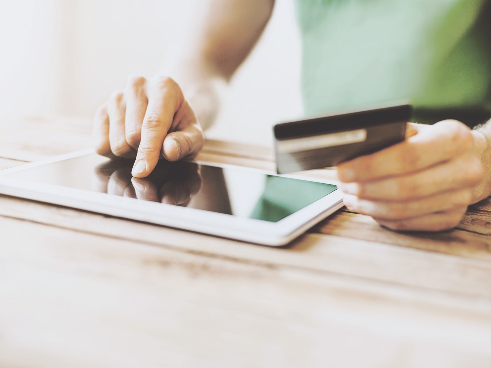 En mand betaler online på sin tablet med sit betalingskort